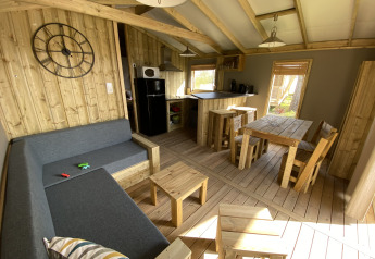 Interior de la Cabane lodge Sweet Flower Premium con muebles de madera y cocina en Flower Camping Le Pré des Sables.