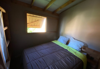 Dormitorio pequeño con cama doble, techo de madera y ventana en Cabane lodge Sweet Flower Premium, Francia.
