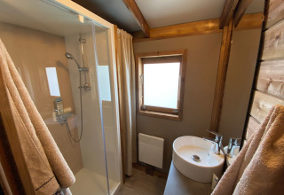 Badkamer met douche en wasbak in een houten chalet bij Cabane lodge Sweet Flower Premium, Frankrijk.