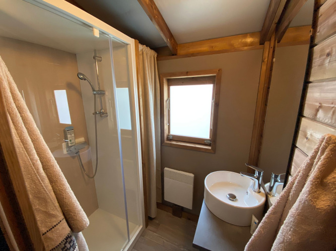 Salle de bain avec douche et lavabo dans un chalet en bois au Cabane lodge Sweet Flower Premium en France.