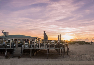 Zandstrand met strandpaviljoen bij zonsondergang in de omgeving van Ouddorp, Zuid-Holland, Nederland.