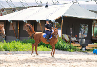 Ruiter op paard bij glamping-tenten op Feather Down Ecuries de Gapennes in Hauts-de-France, Frankrijk.