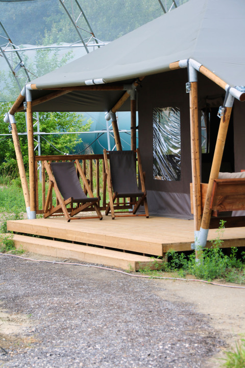 Twee ligstoelen op een houten veranda voor een tent bij Feather Down Ecuries de Gapennes, Hauts-de-France.