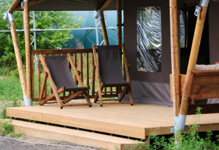 Twee ligstoelen op een houten veranda voor een tent bij Feather Down Ecuries de Gapennes, Hauts-de-France.