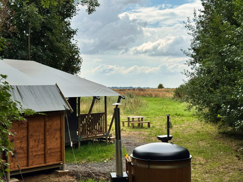 Cabaña de glamping y bañera al aire libre en Feather Down Ecuries de Gapennes, Hauts-de-France, Francia, en la naturaleza.