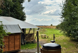 Glamping tent en hottub bij Feather Down Ecuries de Gapennes in Hauts-de-France, Frankrijk, in groene omgeving.