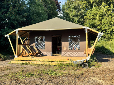 Een glampingtent met houten terras en ligstoelen bij Feather Down Ecuries de Gapennes, Hauts-de-France, Frankrijk.