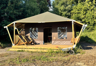 Een glampingtent met houten terras en ligstoelen bij Feather Down Ecuries de Gapennes, Hauts-de-France, Frankrijk.