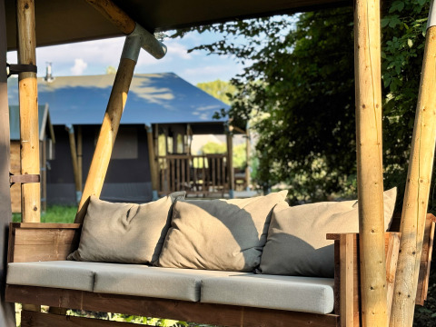 Houten bank met kussens bij Feather Down Ecuries de Gapennes vakantiepark in Hauts-de-France, Frankrijk.