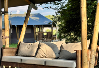 Houten bank met kussens bij Feather Down Ecuries de Gapennes vakantiepark in Hauts-de-France, Frankrijk.