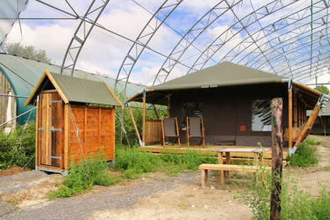 Glampinglocatie bij Feather Down Ecuries de Gapennes in Hauts-de-France met houten hut, tent en zitgedeelte.
