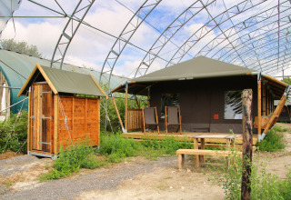 Glampinglocatie bij Feather Down Ecuries de Gapennes in Hauts-de-France met houten hut, tent en zitgedeelte.