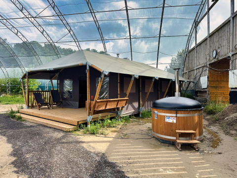 Tienda glamping con terraza de madera y bañera caliente exterior bajo un toldo en Hauts-de-France, Francia.