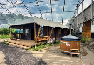 Tienda glamping con terraza de madera y bañera caliente exterior bajo un toldo en Hauts-de-France, Francia.