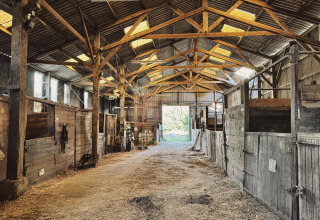 Binnenkant van een rustieke paardenstal bij Feather Down Ecuries de Gapennes, vakantiepark in Hauts-de-France, Frankrijk.
