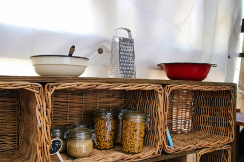 Wicker kitchen shelf with bowls, grater, and jars of dry goods at Feather Down Ecuries de Gapennes, France.