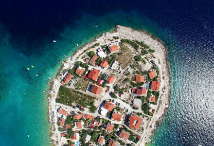 Luftfoto af en kystby nær Umag i Istrien, Kroatien, omgivet af det klare blå vand i Adriaterhavet.