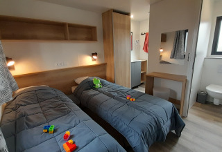 Moderne stacaravan slaapkamer bij Stacaravan Premium, Flower Camping Le Pré des Sables, met twee eenpersoonsbedden.