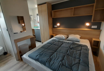 Camera da letto in una Stacaravan Premium al Flower Camping Le Pré des Sables in Francia, con arredi moderni.