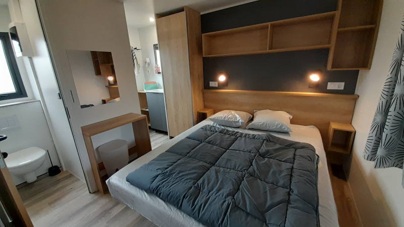 Dormitorio en una Stacaravan Premium en Flower Camping Le Pré des Sables, Francia, con mobiliario moderno.