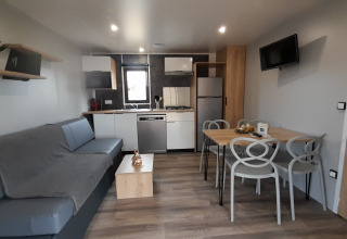 Moderne stue og køkken i en Stacaravan Premium på Flower Camping Le Pré des Sables, Frankrig.