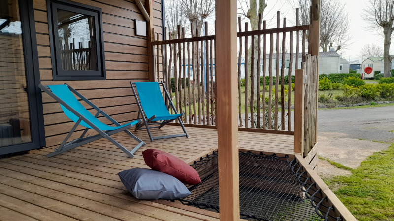 Udendørs terrasse ved en stacaravan på Flower Camping Le Pré des Sables med blå liggestole og puder.