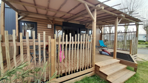 Udendørs træterrasse med stol ved Stacaravan Premium på Flower Camping Le Pré des Sables i Frankrig.