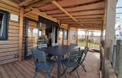 Terrasse en bois couverte avec table et chaises au Stacaravan Premium, Flower Camping Le Pré des Sables.