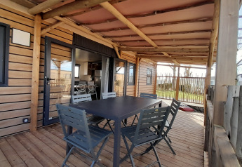 Covered wooden terrace with table and chairs at Stacaravan Premium, Flower Camping Le Pré des Sables, France.