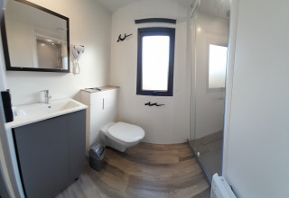Moderne badeværelse i Stacaravan Premium på Flower Camping Le Pré des Sables med toilet, bruser og vask.