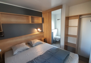 Soveværelse i Stacaravan Premium på Flower Camping Le Pré des Sables, med dobbeltseng og eget badeværelse.