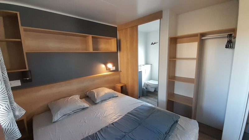 Camera da letto nella Stacaravan Premium al Flower Camping Le Pré des Sables, con letto matrimoniale e bagno privato.