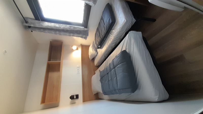 Habitación con dos camas individuales, ventana, estante y suelo de madera en Stacaravan Premium, Flower Camping Le Pré des Sables.