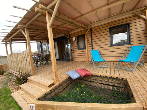 Træveranda med blå liggestole og hængekøjenet på Stacaravan Premium, Flower Camping Le Pré des Sables, Frankrig.