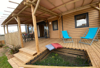 Træveranda med blå liggestole og hængekøjenet på Stacaravan Premium, Flower Camping Le Pré des Sables, Frankrig.