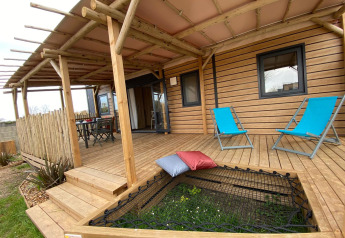 Træveranda med blå liggestole og hængekøjenet på Stacaravan Premium, Flower Camping Le Pré des Sables, Frankrig.