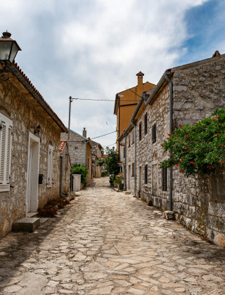 Met stenen geplaveide straat en oude stenen huizen in de omgeving van Vrsar, Istrië, Kroatië, bij bewolkte lucht.