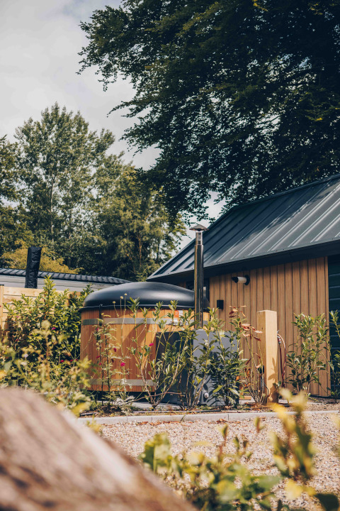 Tiny house in legno con vasca idromassaggio e tetto scuro al Veluwepark de Bosgraaf, Paesi Bassi.