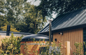 Tiny house in legno con vasca idromassaggio e tetto scuro al Veluwepark de Bosgraaf, Paesi Bassi.
