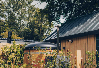 Tiny house en bois avec bain à remous à Veluwepark de Bosgraaf, entourée de verdure aux Pays-Bas.