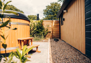 Outdoor area of Tiny Loft with hot tub and wood siding at Veluwepark de Bosgraaf, Netherlands.