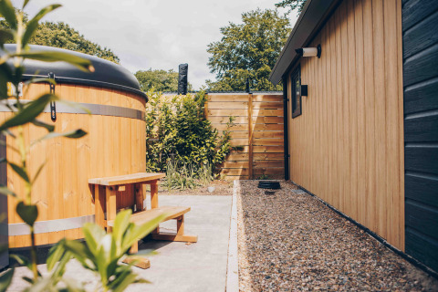 Outdoor area of Tiny Loft with hot tub and wood siding at Veluwepark de Bosgraaf, Netherlands.