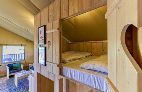 Interior de madera acogedor con cama en nicho y área de estar en la Safarilodge Gazelle, parque IJsselhof.