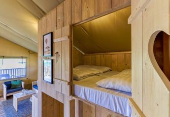 Intérieur en bois chaleureux avec lit en alcôve et coin salon dans la Safarilodge Gazelle, IJsselhof.