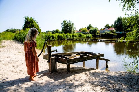 Una niña con vestido rojo junto a una bomba de agua en un lago en Safarilodge Impala, IJsselhof, Países Bajos.