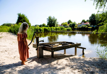Una bambina con un vestito rosso accanto a una pompa d’acqua al lago di Safarilodge Impala, IJsselhof, Paesi Bassi.