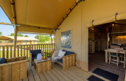 Terrasse en bois couverte à Safarilodge Gazelle, Vakantiepark IJsselhof, Pays-Bas, avec salon extérieur.