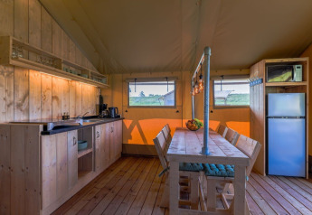 Cucina e zona pranzo in legno nella tenda Safarilodge Gazelle al Vakantiepark IJsselhof, Paesi Bassi.