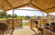 Blick von der Terrasse des Safarilodge Impala im Vakantiepark IJsselhof, Niederlande, mit Holzmöbeln.