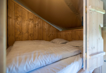 Gemütliche Schlafnische mit Holzwänden im Safarilodge Impala, Ferienpark IJsselhof, Niederlande, mit Bett.